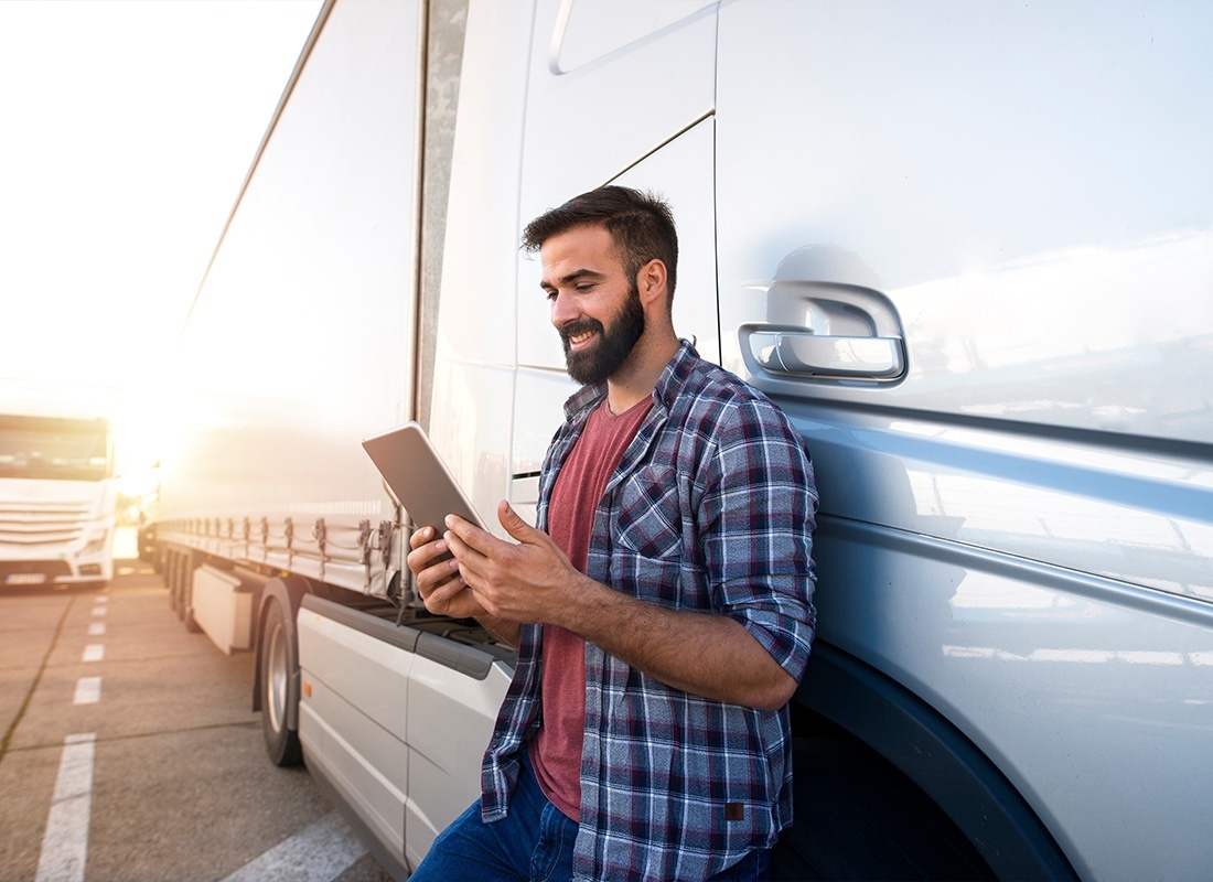 Business Insurance.- Professional Truck Driver Checking His Route on a Tablet